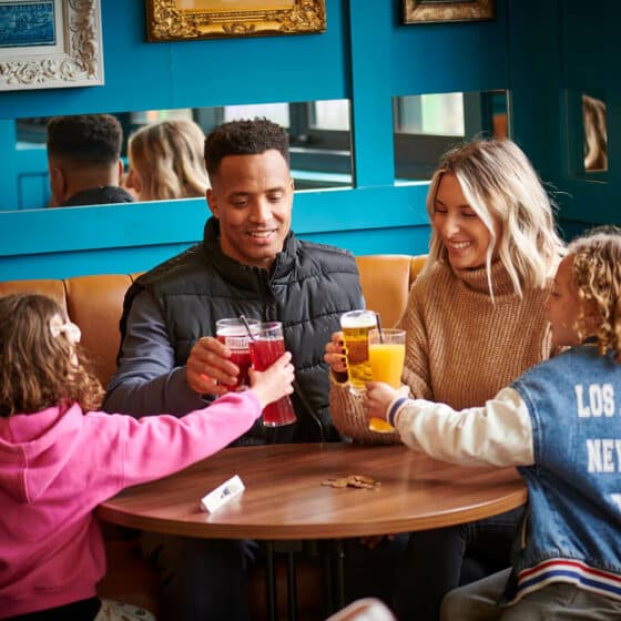 A family of four enjoying a drink in the Explorer's Bar & Coffee Shop at Fantasy Island theme park resort