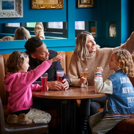 A family of four enjoying a drink in the Explorer's Bar & Coffee Shop at Fantasy Island theme park resort
