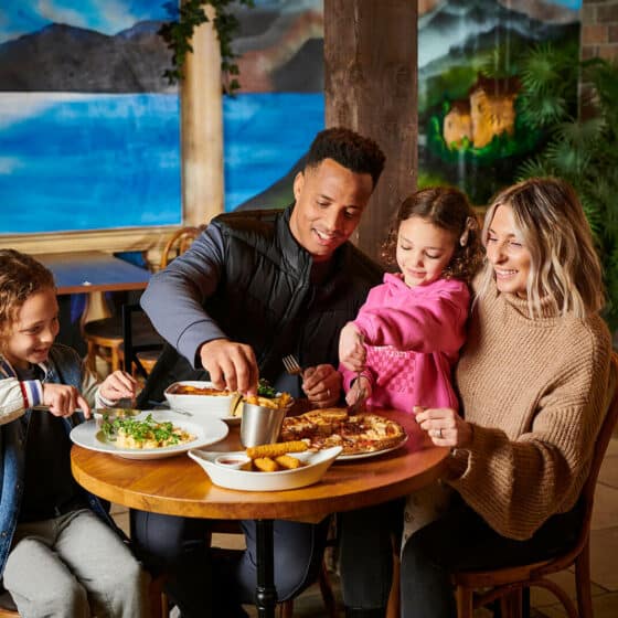 A family of four enjoying a meal in the Explorer's Bar & Coffee Shop at Fantasy Island theme park resort